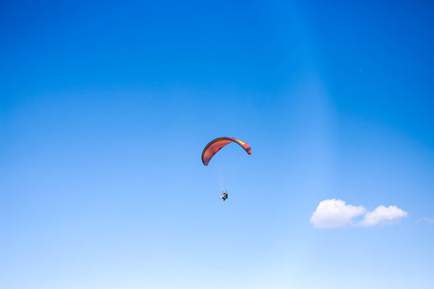 一个年轻人在晴朗多云的天气里滑翔伞图片下载