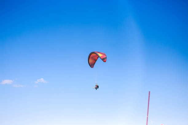 一个年轻人在晴朗多云的天气里滑翔伞图片下载