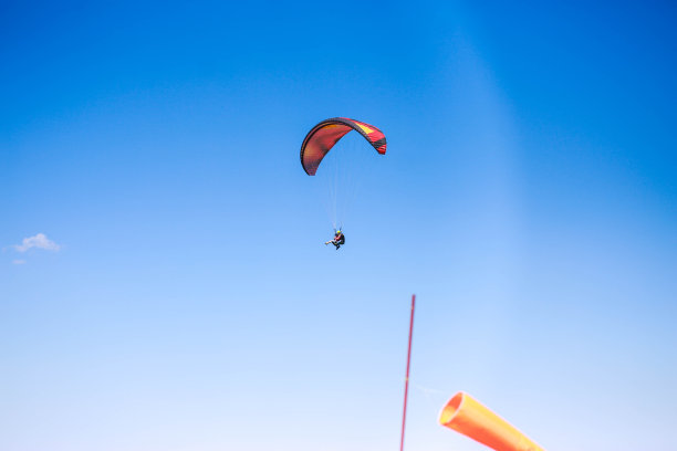 一个年轻人在晴朗多云的天气里滑翔伞图片下载