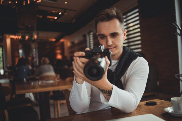 一名男子在咖啡馆用相机拍照图片下载