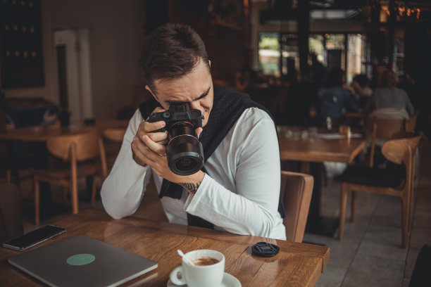 一名男子在咖啡馆用相机拍照图片下载