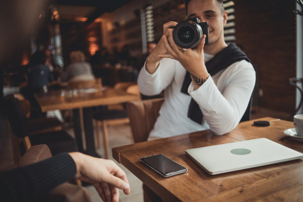一名男子在咖啡馆用相机拍照图片下载