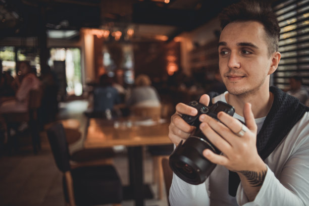 一名男子在咖啡馆用相机拍照图片下载