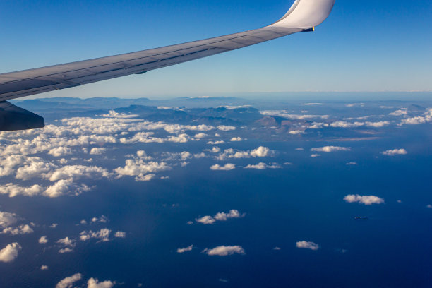 蓝天和白云，从大气到陆地和海洋形成了一道美丽的风景，背景是飞机的机翼和岛屿，以及海上的一艘船。图片下载