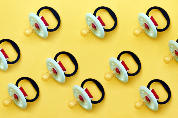 黄色背景上的婴儿奶嘴，特写图片下载