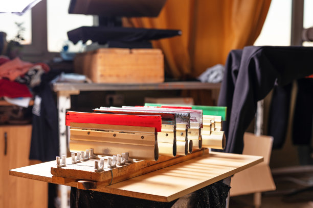 木架上的橡皮刮。绢印生产。在设计工作室用丝印法在t恤上印刷图案图片下载