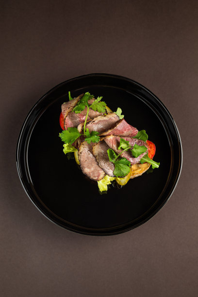 烤鸡胸肉，肉片和新鲜蔬菜，黑色的碗，深色的背景。图片下载