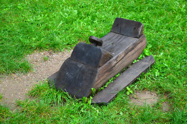 在公园里雕刻机器或水上或雪地滑板车形状的玩具。草坪上有木制的产品和方向盘，还有用木杆制成的马车图片下载