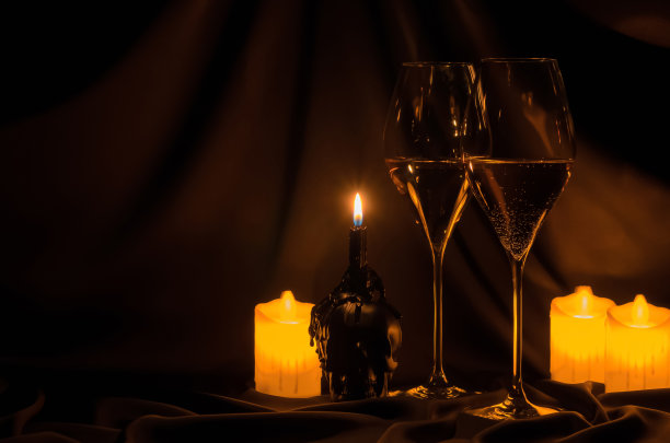 酒杯与模糊焦点的头骨和蜡烛在黑暗的布背景。图片下载