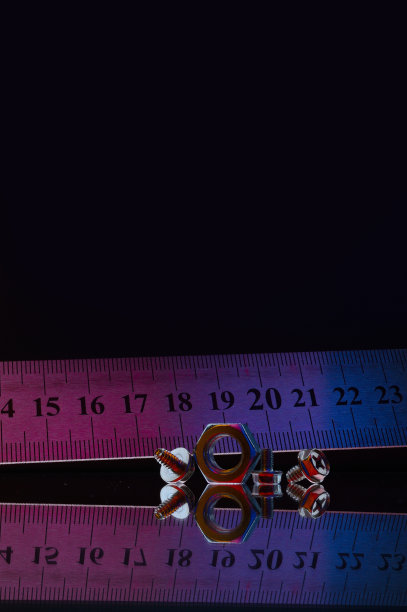 金属组成，不同尺寸镀铬螺母和一把金属尺。黑色背景。图片下载