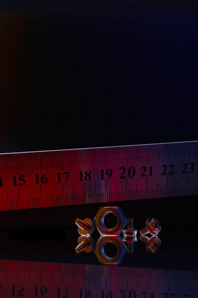 金属组成，不同尺寸镀铬螺母和一把金属尺。黑色背景。图片下载