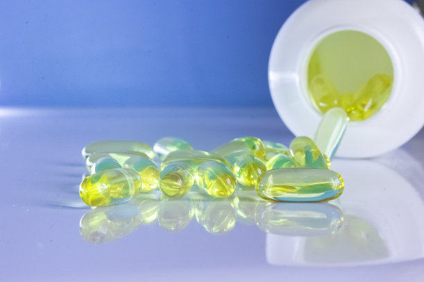 一罐欧米茄3维生素，维生素在桌子上，一个木勺欧米茄3维生素在一个蓝色的背景，一个健康的生活方式的概念，膳食补充剂，维生素，健康图片下载