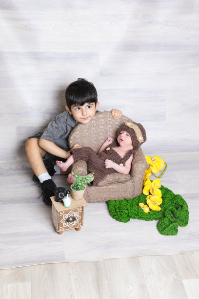 两个表情俏皮的兄妹儿童，可爱的男婴戴着棕色针织帽图片下载