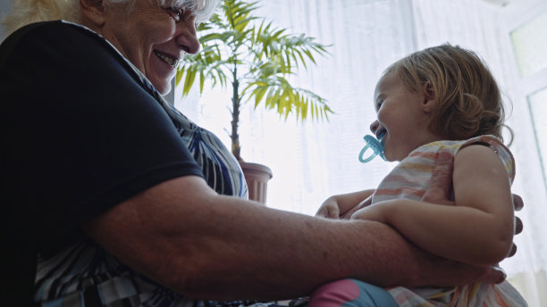 在行动。奶奶把女婴抱在膝上。图片下载