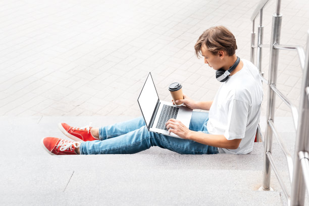 穿着红色运动鞋的家伙坐在户外的台阶上，手里拿着笔记本电脑。有选择性的重点图片下载