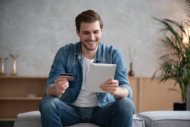 手拿信用卡，使用数码平板电脑。网上购物的概念。图片下载