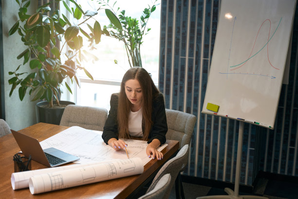 设计专业人员坐在办公桌前分析楼层平面图图片下载