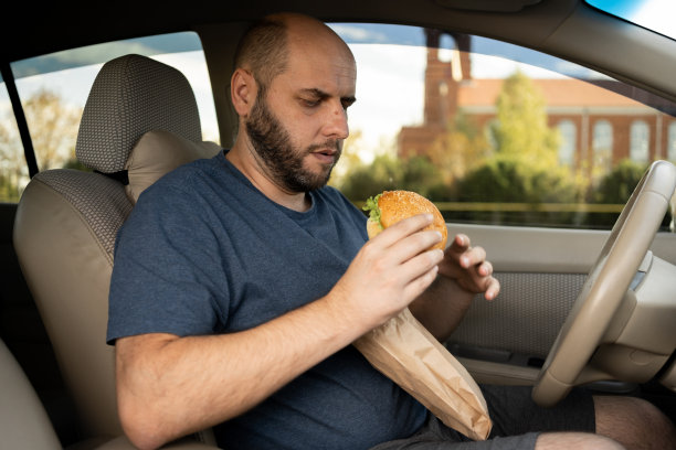出租车司机在车里吃汉堡，因为早上交通很糟糕。在车里吃汉堡图片下载