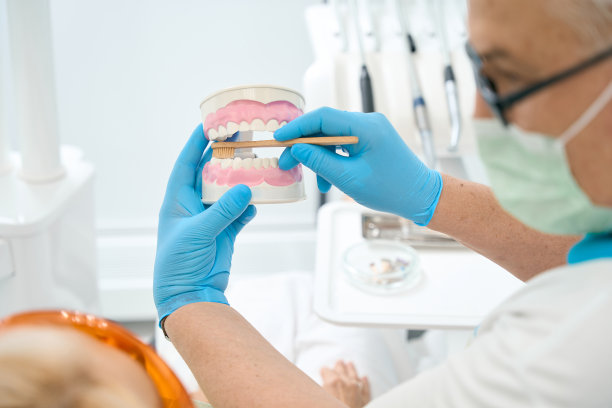 牙齿模型和牙刷在正畸医生手中的详细照片隔离在牙科办公室背景图片下载