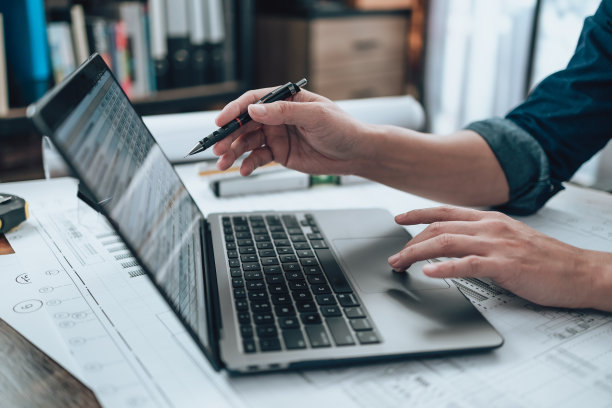 在办公室的笔记本电脑上进行图纸检查，在图纸上使用计算器，三角尺，安全眼镜，指南针，游标卡尺。工程师，建筑师，工业和工厂概念。图片下载