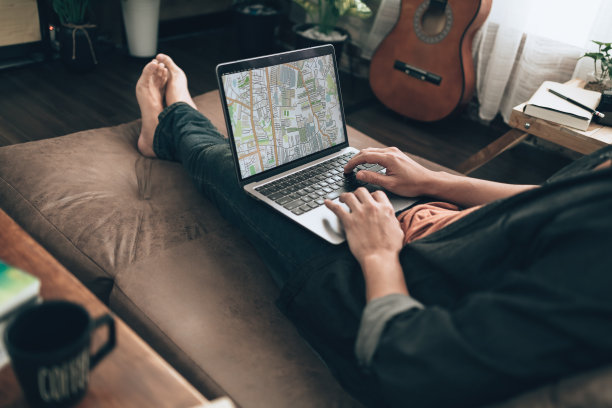 旅行者计划旅行，在家里客厅的沙发床上用笔记本电脑预订酒店、购买机票、搜索地图或查找旅行路线。旅行的概念。图片下载