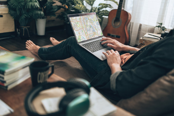 旅行者计划旅行，在家里客厅的沙发床上用笔记本电脑预订酒店、购买机票、搜索地图或查找旅行路线。旅行的概念。图片下载