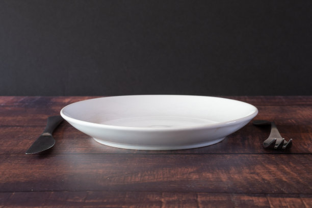 一个人的餐具，刀叉在一个白色的盘子旁边。图片下载