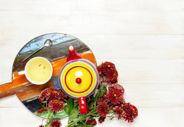 一杯热腾腾的花草茶，木托盘上鲜艳的茶壶黑板，针织格纹或毛衣红色的菊花在轻木制背景俯瞰抄写空间舒适的早餐在家里图片下载