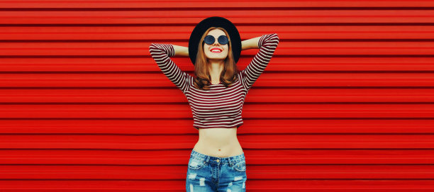 肖像时尚快乐微笑年轻女子戴黑色圆帽在红色背景，空白复制空间图片下载