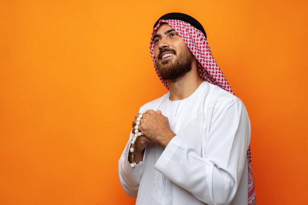 年轻的阿拉伯人拿着传统的珠子，背景是橙色图片下载
