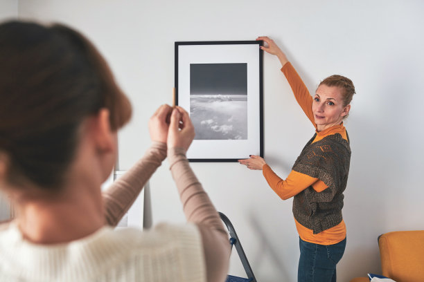 母女俩在家里挂图画和照片。图片下载
