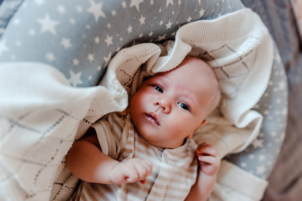 穿着白色格纹衣服的新生儿。婴儿在茧里。图片下载