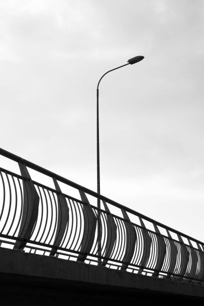 长长的金属道路围栏，在明亮的天空下，有一盏高高的路灯图片下载