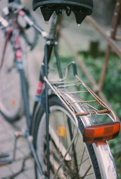 特写镜头的金属后座停放的自行车在雨与模糊的背景图片下载