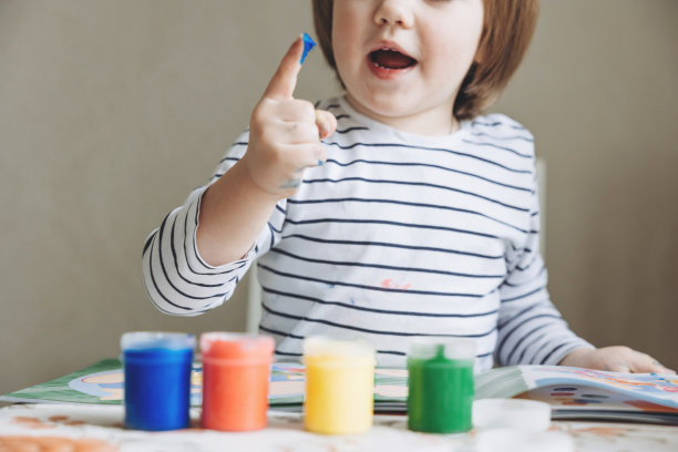 手指绘画。可爱的小男孩在家里用手指画画的肖像。孩子的手在彩色颜料中的特写。早期教育的概念。感觉玩。精细运动技能的发展。图片下载