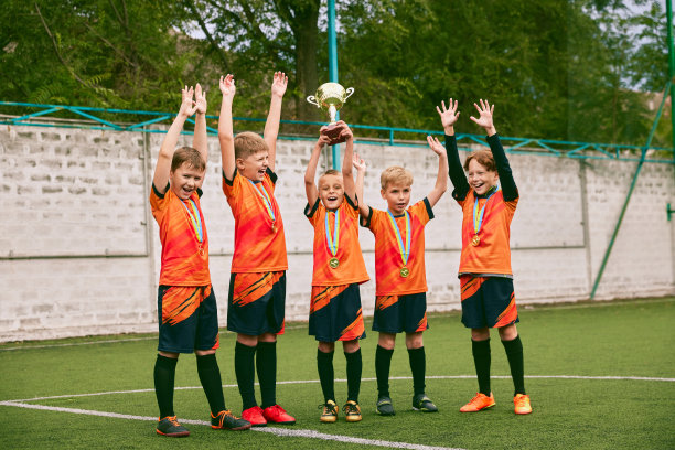 足球青年队的奖牌和奖杯。欢快的男孩庆祝胜利。赢的概念，运动，学习，成就，成功。图片下载