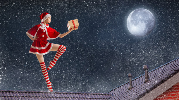 圣诞夜，在满天繁星的背景下，身穿圣诞老人服装、手拿礼物的芭蕾舞女演员站在屋顶上。图片下载