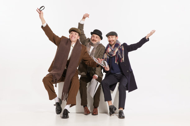 三个穿着大衣的时髦男人的肖像在灰色背景下摆姿势。表现出愉快和兴奋的情绪图片下载