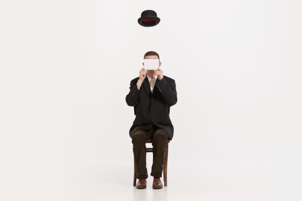 肖像的时尚男子在棕色西装坐在椅子上孤立的白色工作室背景。飞行帽图片下载