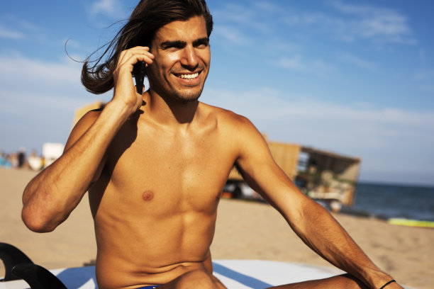 海滩上一个拿着冲浪板的年轻人。图片下载