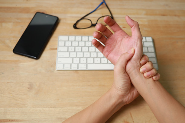 在电脑前工作时，手腕疼痛、麻木或腕管综合症的妇女用手握住疼痛的关节图片下载