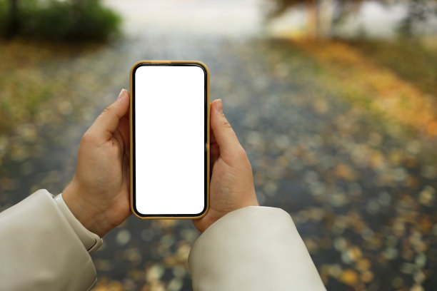 秋天公园的街道上，手里拿着独立屏幕的手机图片下载