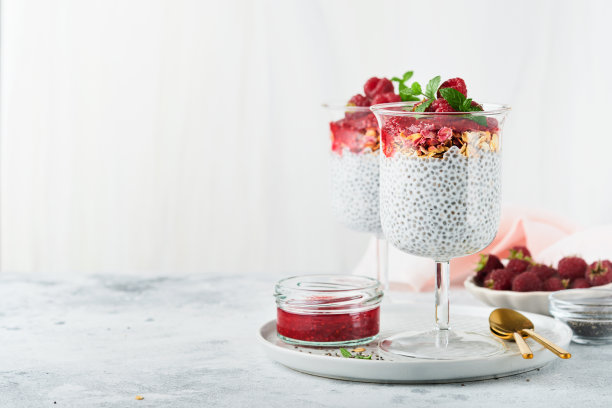 贾布丁。健康的香草奇亚布丁在玻璃与新鲜的覆盆子和薄荷在白色的背景。素食健康的早餐。图片下载