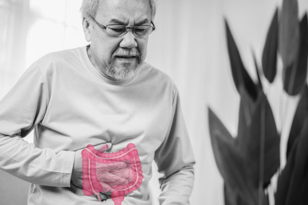 亚洲老年男子感到胃痛。年长的成年男性坐在家里客厅的沙发上摸肚子。肠道问题保健和医疗保险的概念。图片下载