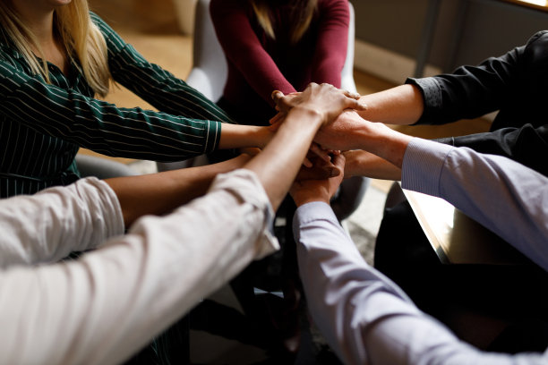 积极多元的业务团队把手放在对方的上面，显示出团结和团队精神图片下载