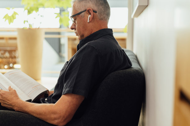 商人戴着耳机在办公室看书图片下载