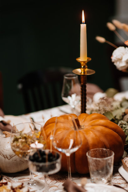 用秋天的装饰、蜡烛、鲜花和南瓜装饰和服务节日的桌子。图片下载