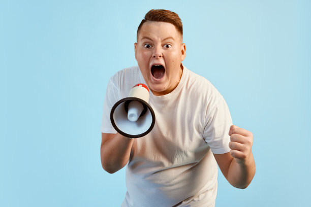 注意,新闻。兴奋的小男孩对着蓝色背景上孤立的扩音器大喊大叫。情感概念，面部表情，青春，抱负，销售图片下载