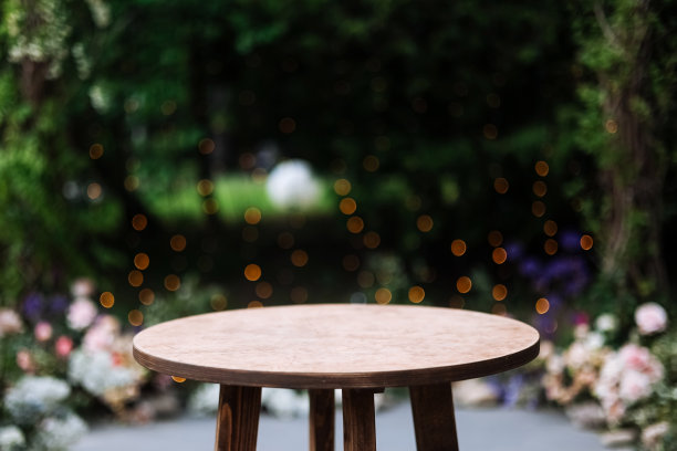 圆形木桌上的绿色自然灯泡背景。户外桌子在书桌。背景中的草、绿色植物和派对装饰灌木。图片下载