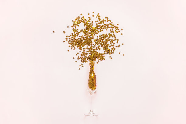 圣诞组成。香槟杯里洒出金色的星星，撒上粉红色的彩纸。新年假期概念。明信片图片下载